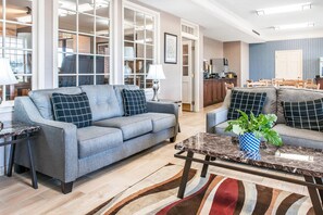 A living room with a grey sofa, a coffee table, and a dining area with chairs. - Quality Inn Findlay (Findlay)