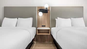 Habitación de hotel con dos camas, cabecera de madera, mesita de noche y lámpara de pared.