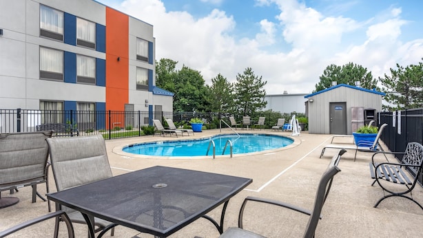 A pool area with lounge chairs, a table, and a building with a blue and orange facade. - Best Western Inn Florence (Florence)