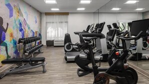 Une salle de sport équipée de divers appareils d’exercice, notamment des tapis de course, des vélos d’appartement et des haltères.