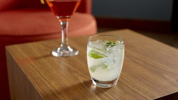 A glass of a light-colored beverage with mint leaves on a wooden table.