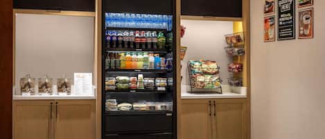 Un área de comida autoservicio con bebidas refrigeradas, bocadillos y comidas preparadas.