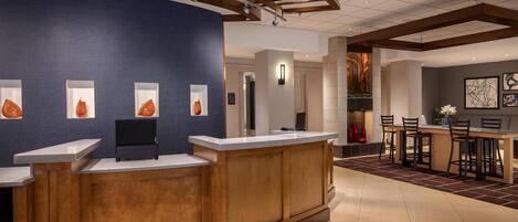 A reception area with a wooden reception desk, a blue accent wall, and framed artwork.