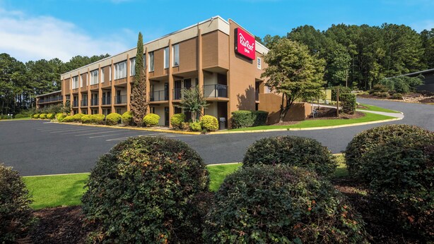 A Red Roof Inn with a parking lot, surrounded by well-maintained landscaping and trees. - Red Roof Inn Atlanta Airport NE - Conley (Conley)