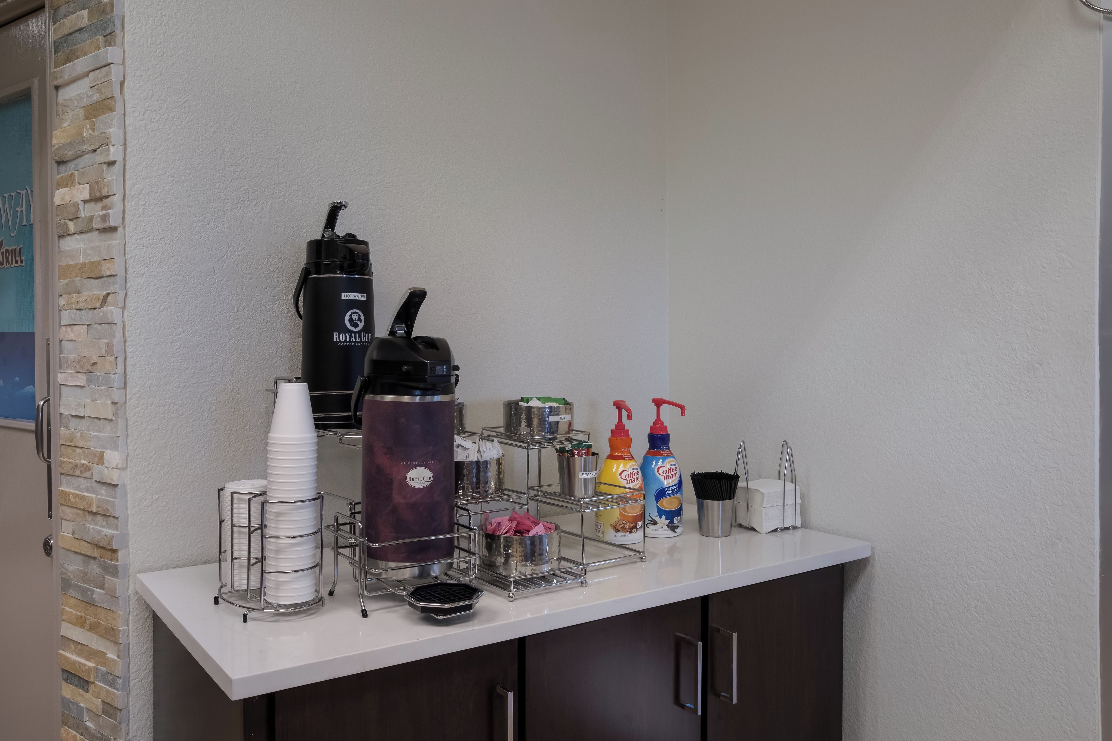 A bar area with a coffee machine, disposable cups, and condiments.