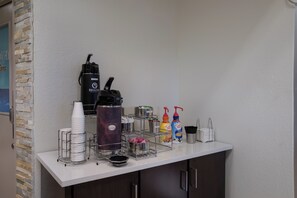 Una zona de bar con una máquina de café, vasos desechables y condimentos.