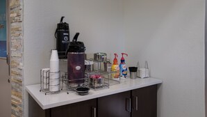Un coin café équipé d’une machine à café, de tasses et de divers condiments.