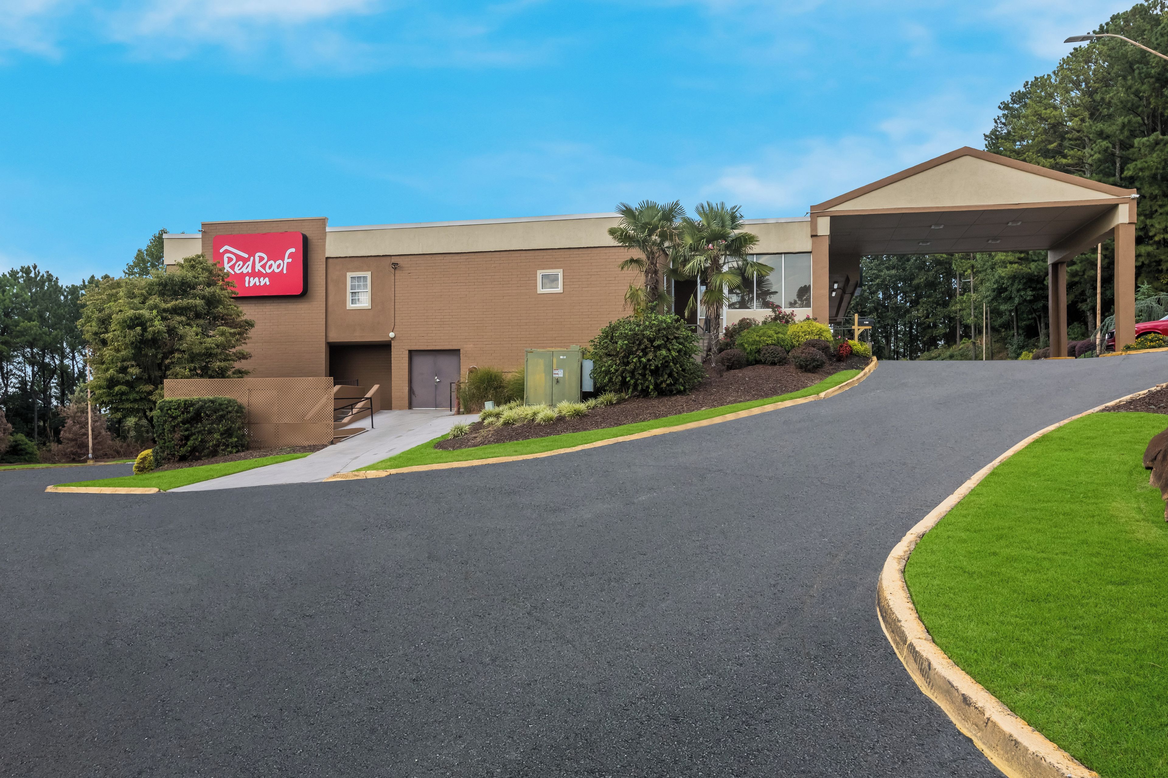 A Red Roof Inn with a covered parking area and a landscaped entrance.