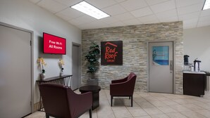 Un espace d’accueil doté d’un téléviseur à écran plat affichant le message « Wi-Fi gratuit dans toutes les chambres », d’une enseigne Red Roof Inn et d’une affiche pour Castaway Beach and Golf.