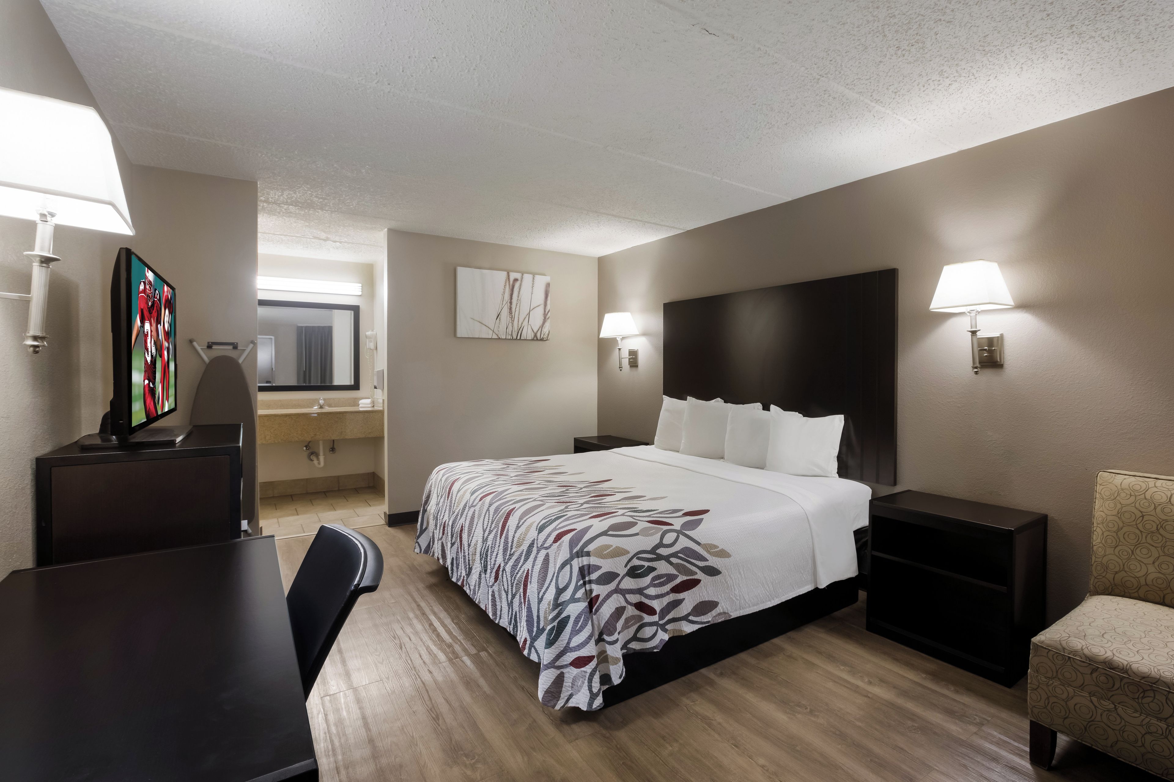Una habitación de hotel con cama, mesitas de noche, escritorio, silla y televisión.