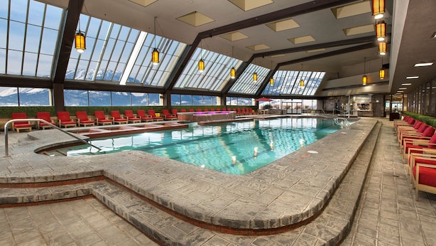 Ein Hallenbad mit Blick auf schneebedeckte Berge durch große Fenster.