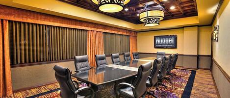 Una sala de conferencias con una gran mesa, sillas de cuero, alfombra estampada, techo de madera y un letrero que dice 'Nugget Casino Resort'.