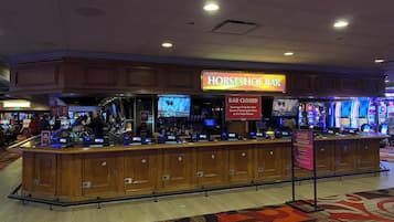 Zona de bar con un cartel que dice “Horseshoe Bar” y un cartel que indica “Bar Cerrado”. Se observan máquinas de juego y una pantalla de televisión al fondo.