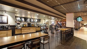 Ein großzügiges Café mit mehreren Sitzbereichen, einer Theke mit verschiedenen Artikeln und dem Starbucks-Logo.