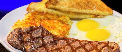 A plate with a steak, two fried eggs, hash browns, and toast.