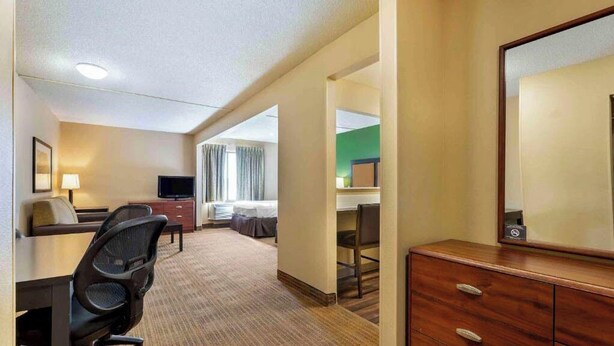 Une chambre d’hôtel équipée d’un bureau, d’une chaise, d’une télévision, d’un lit et d’un miroir.