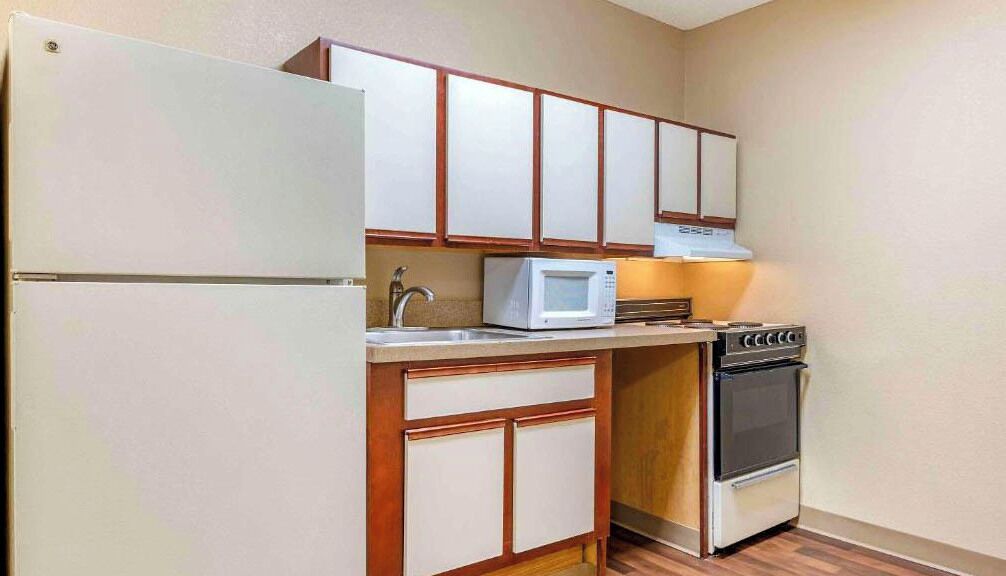 A compact kitchen with a refrigerator, microwave, stove, and wooden cabinets.