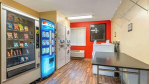 Une petite cuisine équipée d’un réfrigérateur, d’un four à micro-ondes et d’un distributeur automatique.