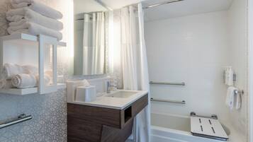 A modern bathroom with a shower, a sink, and a vanity with towels.