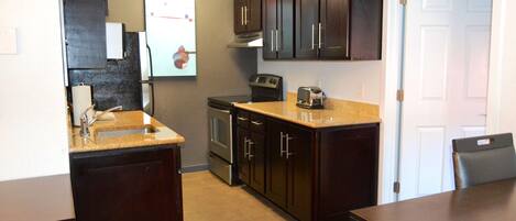 A compact kitchen with dark wood cabinets, a built-in oven, a microwave, and a sink.