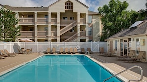 A pool area with lounge chairs and a building with multiple balconies. - HYATT house Mt. Laurel (Mount Laurel)
