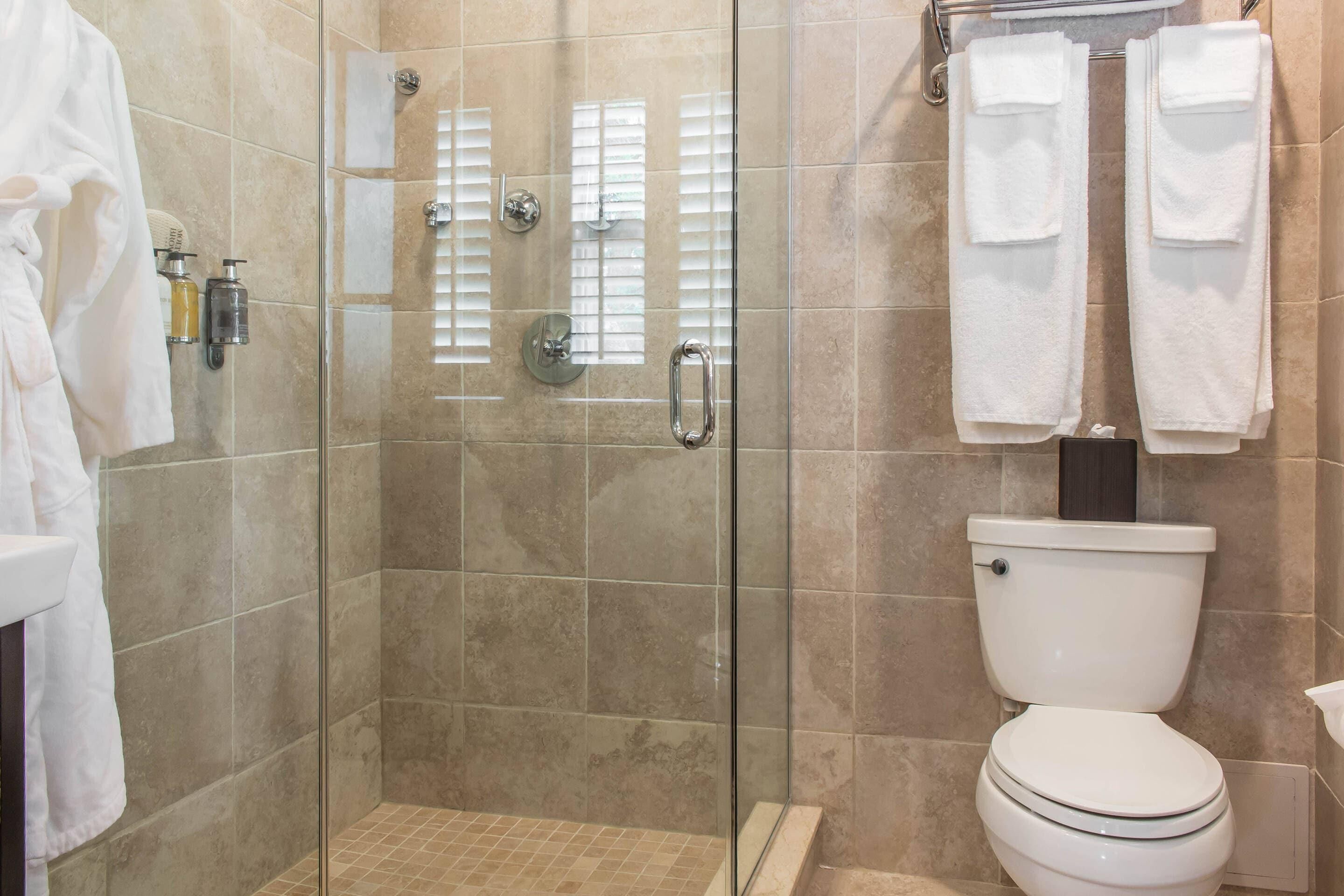 A bathroom with a glass-enclosed shower, a toilet, and a sink.