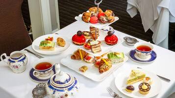 A table set with a variety of pastries, sandwiches, and tea cups, suggesting a tea service or buffet.
