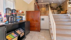 A coffee station with espresso machines, a wooden cabinet, and snack bins.