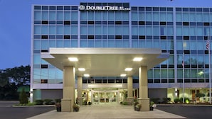 Ein modernes Hotel mit Glasfassade, überdachter Eingangspartei und einem Schild mit der Aufschrift "DOUBLETREE by Hilton".