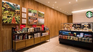 Ein Starbucks-Innenausblick mit Holzvertäfelung, einer Vitrine mit Gebäck und einem Kaffeebohnenregal.