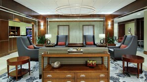Eine Lobby mit einer Rezeption, zwei Sesseln, einem Couchtisch und einem gemusterten Teppich.