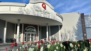 A building with a sign reading "Queensbury" and "The Queensbury Hotel" with columns and a covered entrance. - The Queensbury Hotel (Glens Falls)