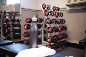 Une salle de sport équipée de divers appareils de musculation, notamment des haltères et un banc.