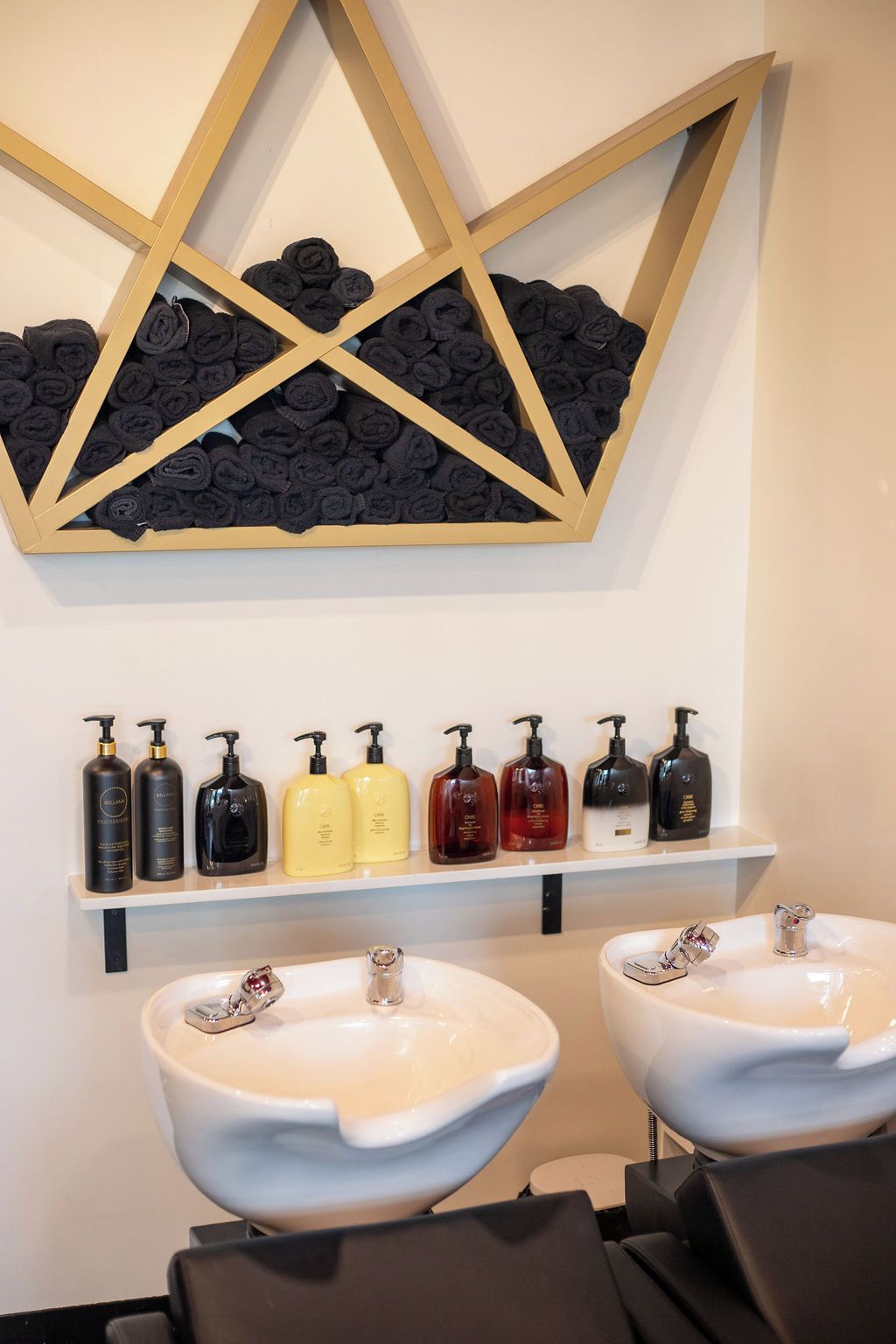 A bathroom with two sinks, a shelf with toiletries, and a wall-mounted towel rack.