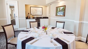 A dining room with a round table set for four, featuring white tablecloths, black napkins, and silverware. - The Queensbury Hotel (Glens Falls)