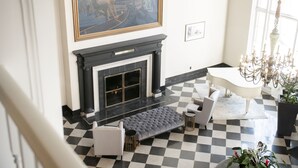 A checkered floor, a fireplace, a dining table, and a chandelier in a room with a painting on the wall. - The Queensbury Hotel (Glens Falls)