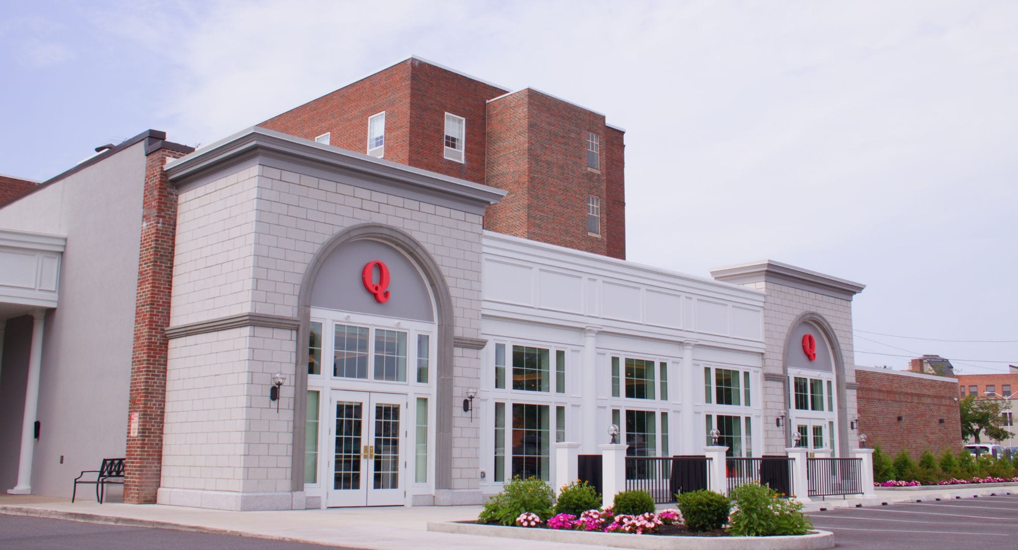 A building with a prominent red 'Q' logo, large windows, and a brick facade.