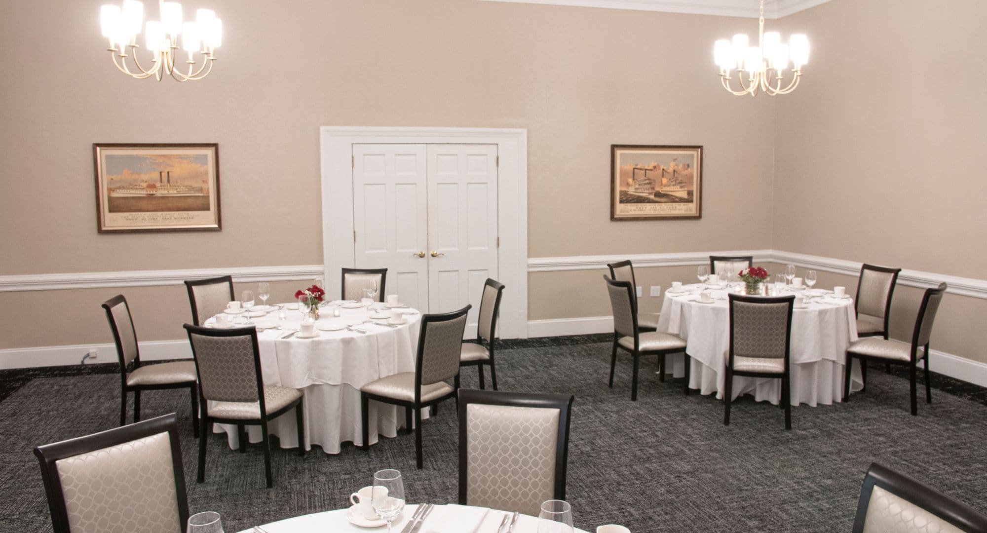 Une salle de conférence avec des tables rondes, des chaises et des lustres.