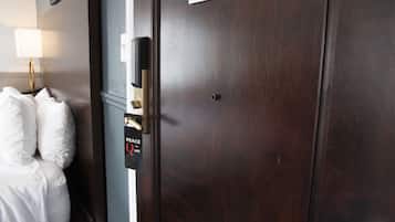A hotel room with a bed, a nightstand, a lamp, and a door with a 'Peace Quiet' sign.