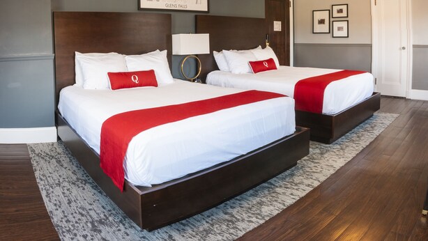 A hotel room with two beds, a map on the wall, and a door. - The Queensbury Hotel (Glens Falls)