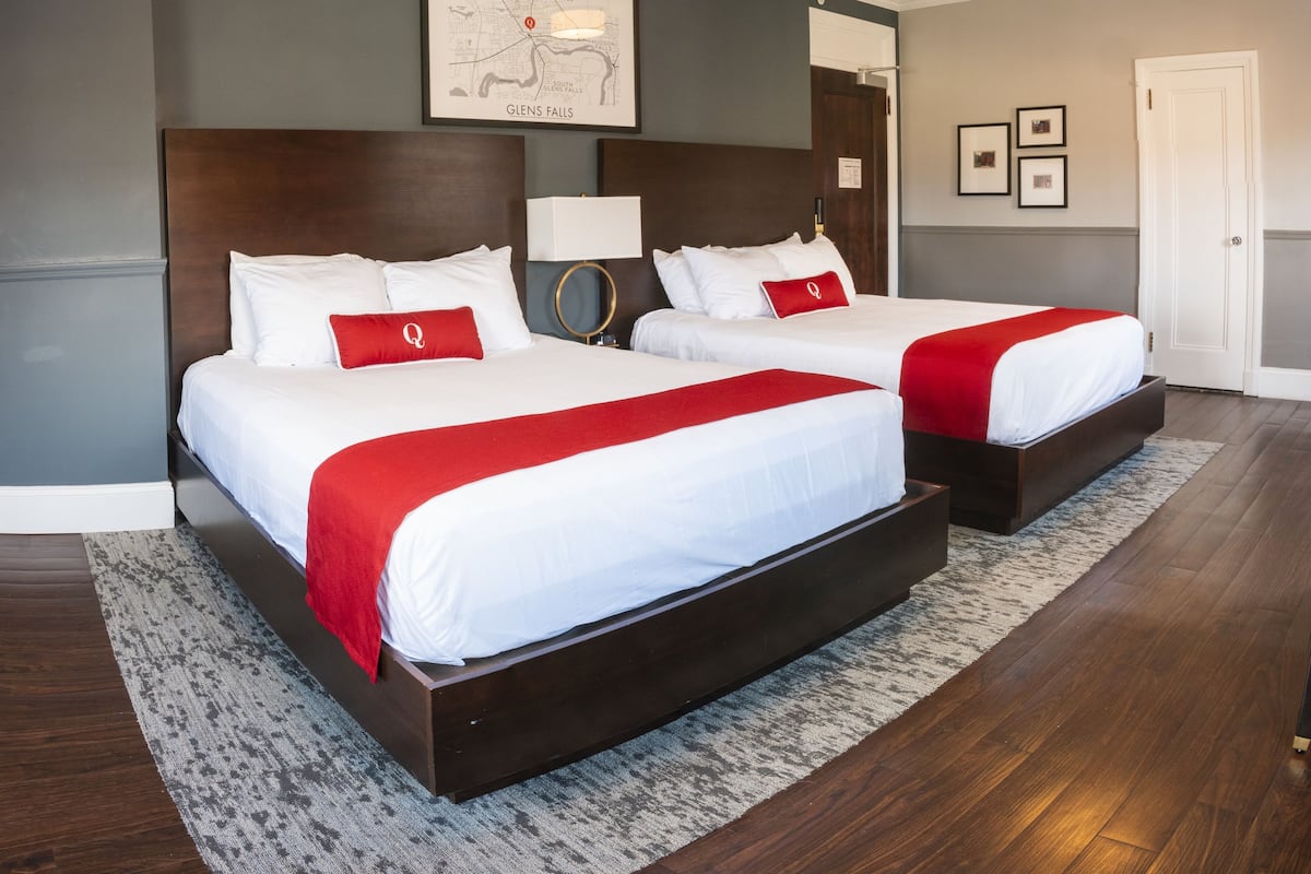 A hotel room with two beds, a map on the wall, and a door.