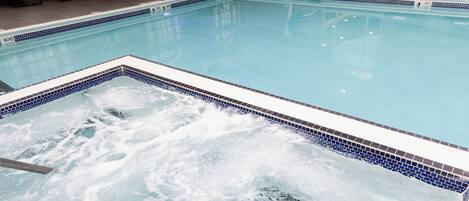 A swimming pool with a tiled edge, lounge chairs, and a lifeguard stand.