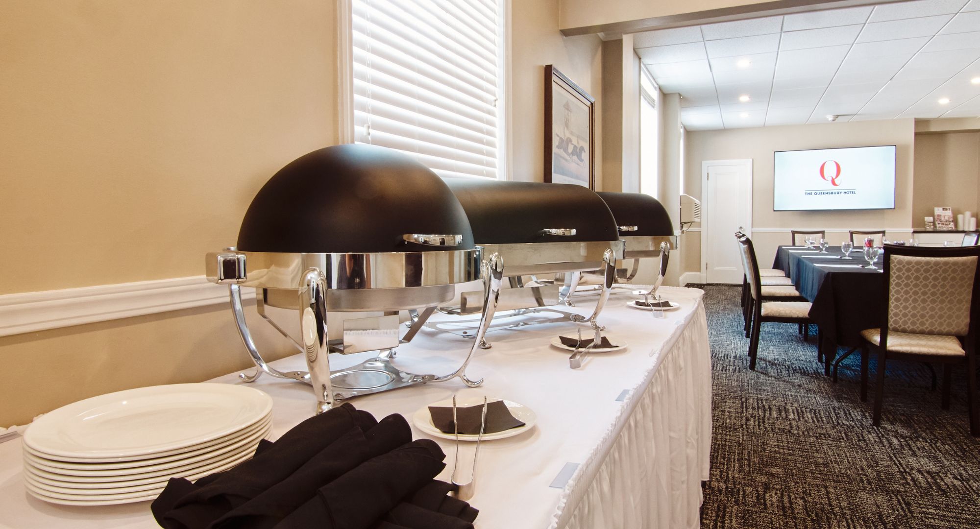 A conference room with a long table set for a meeting, equipped with black lamps, white plates, and black napkins.