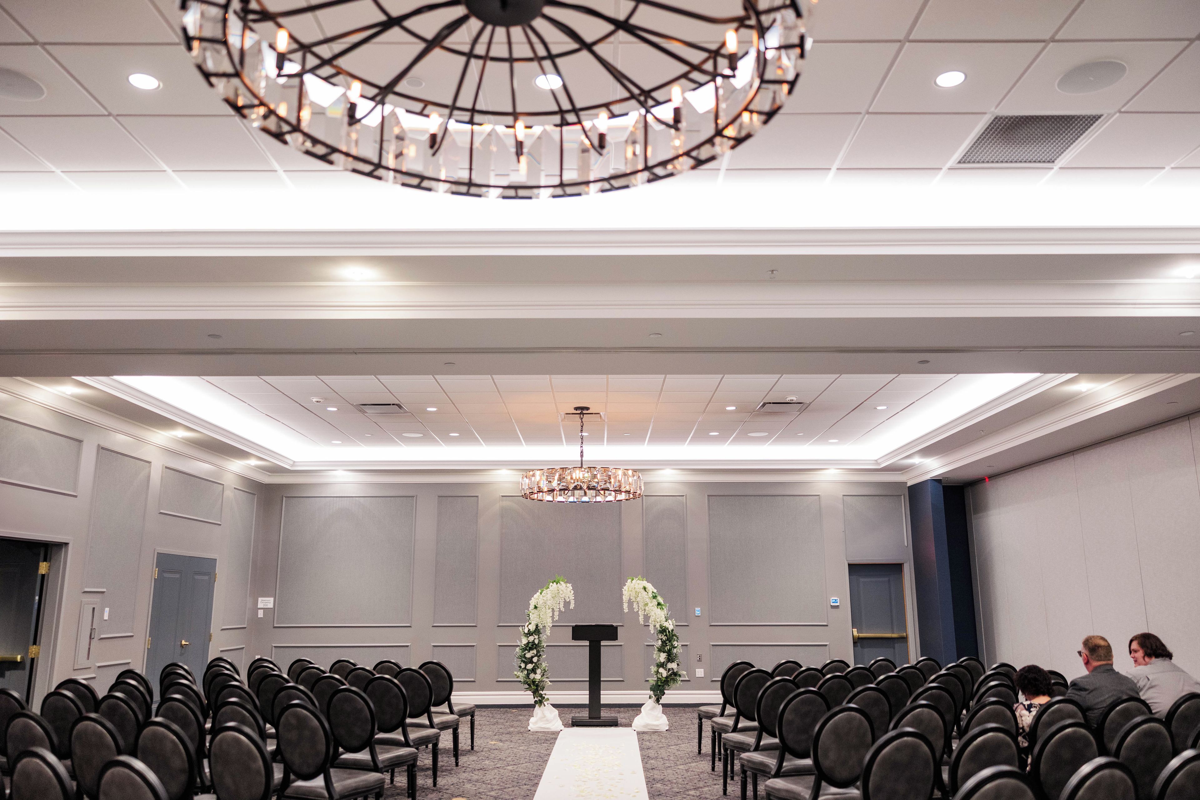 A conference room with rows of chairs, a podium, and a chandelier.