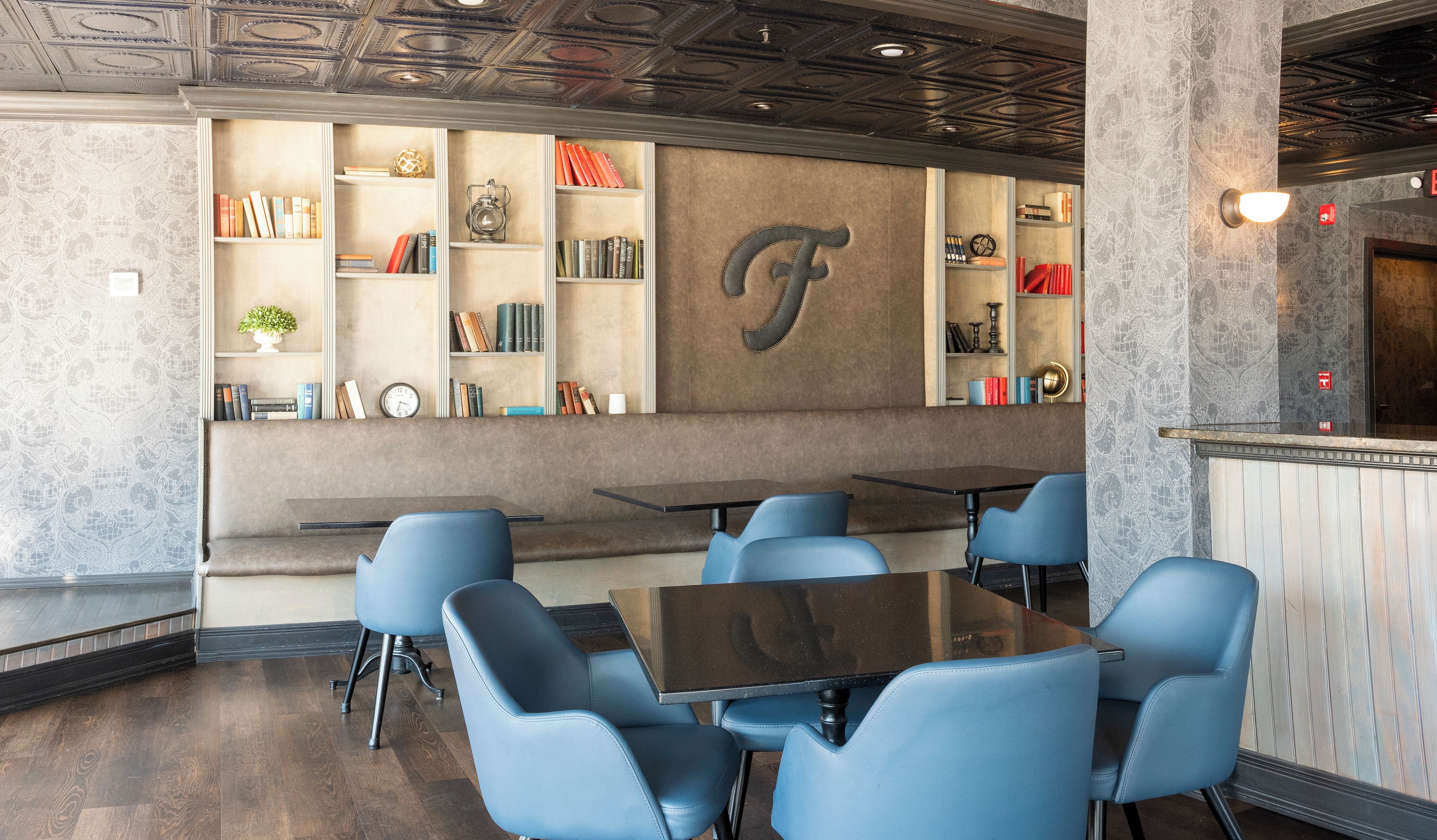 A restaurant interior with a bar area, seating, and a decorative wall with a large letter 'F'.