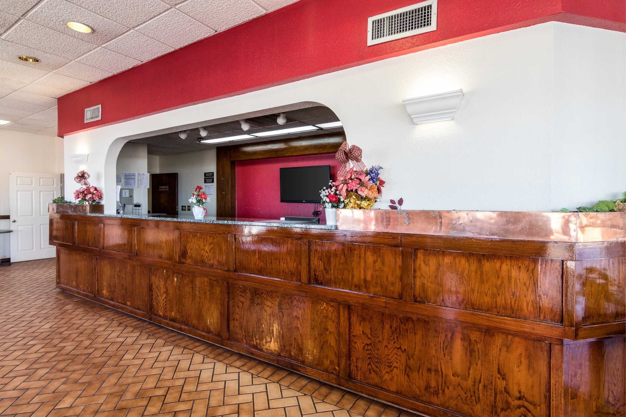 A reception area with a wooden counter, a red wall, and a tiled floor.