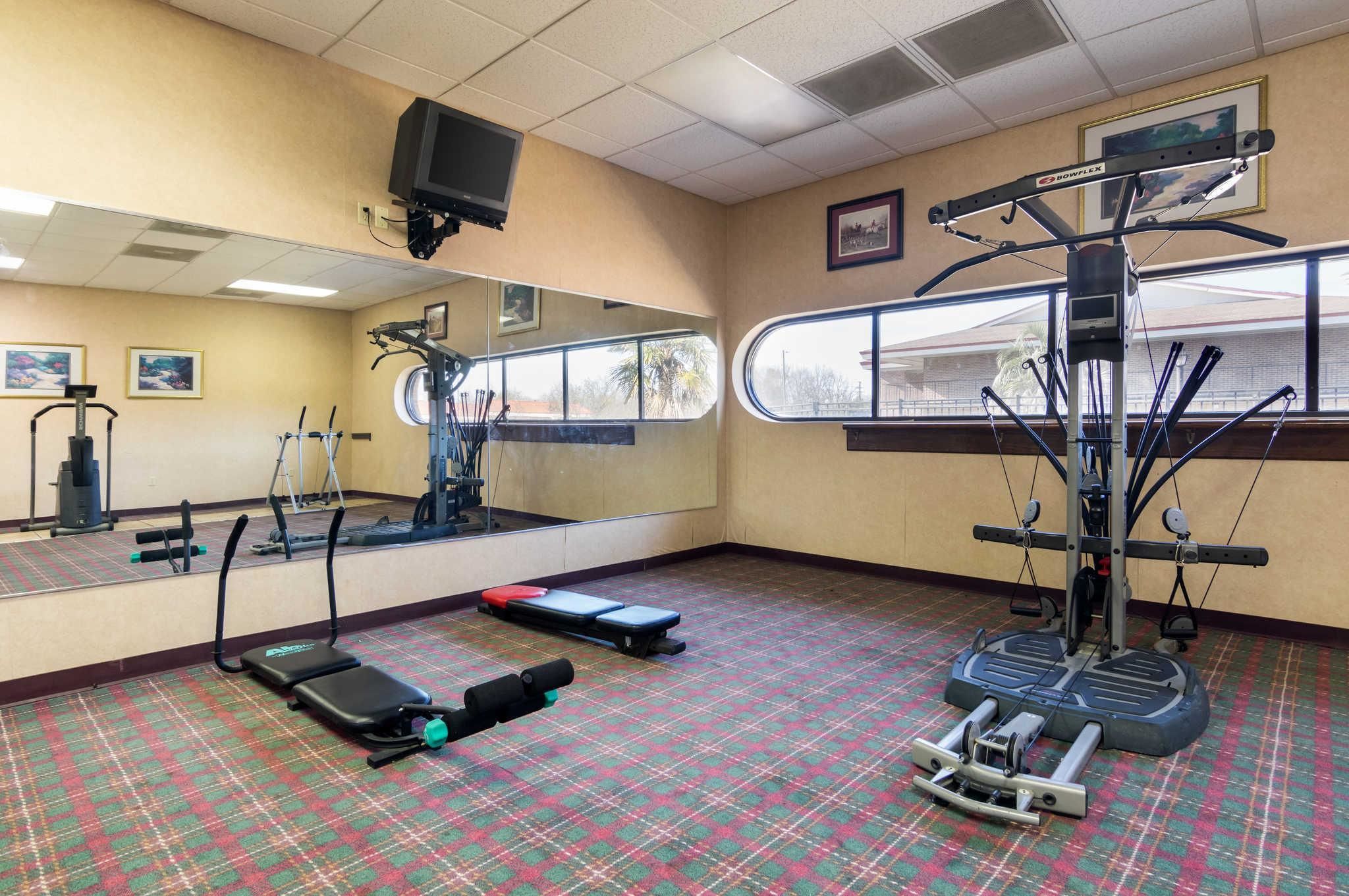 A gym with exercise equipment, a large mirror, and a window.
