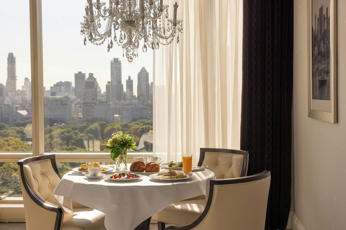 Una mesa de comedor con vistas a un horizonte urbano a través de amplias ventanas.