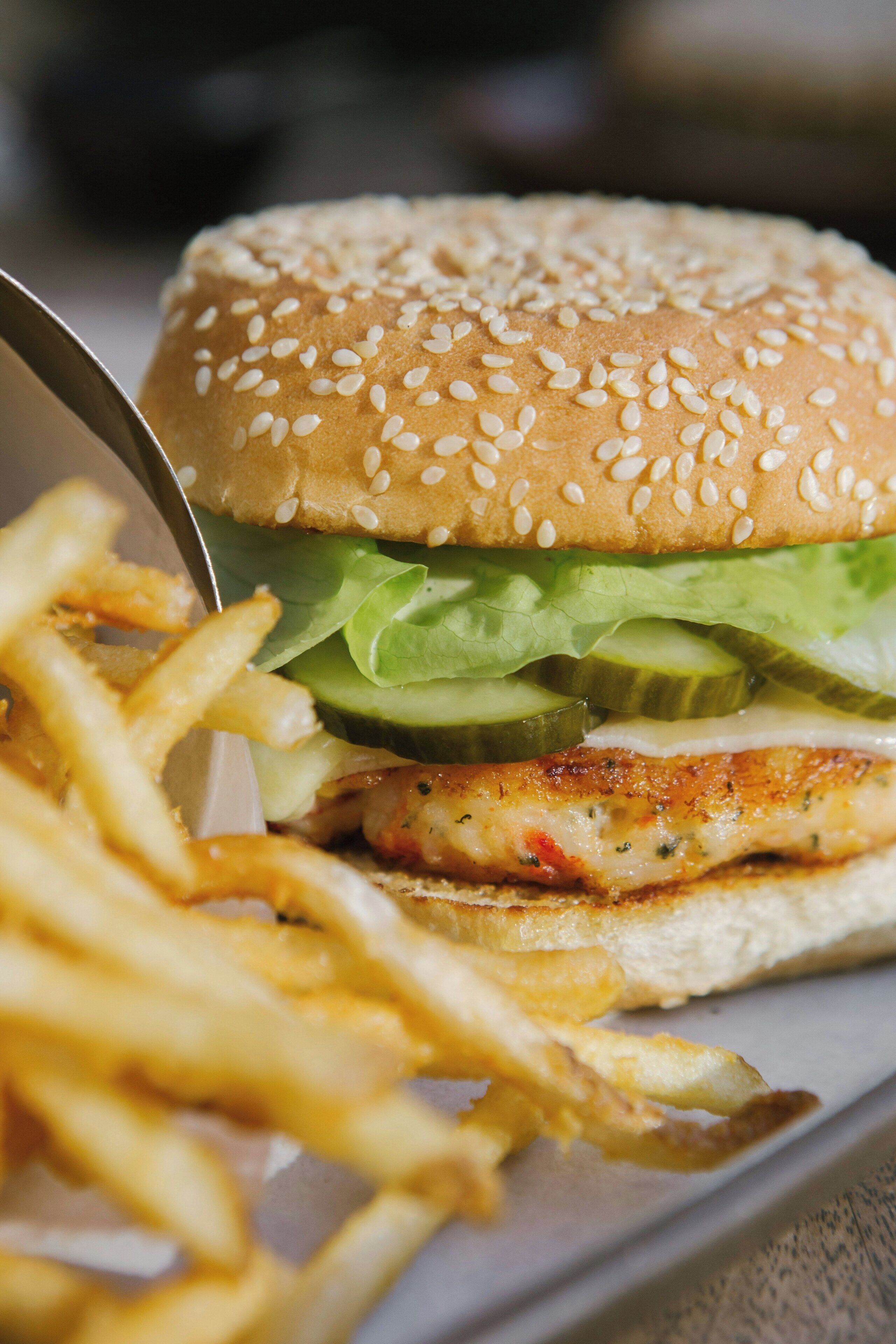 A sandwich with lettuce and a bun, alongside a portion of fries.