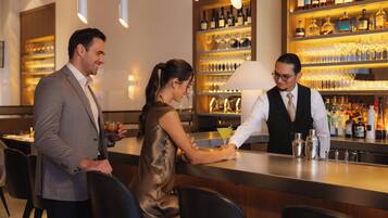 Zona de bar con un cantinero, un hombre y una mujer sentados.